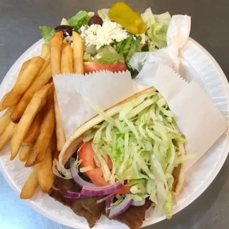 A Greek gyro with fries and a side salad on a white plate.